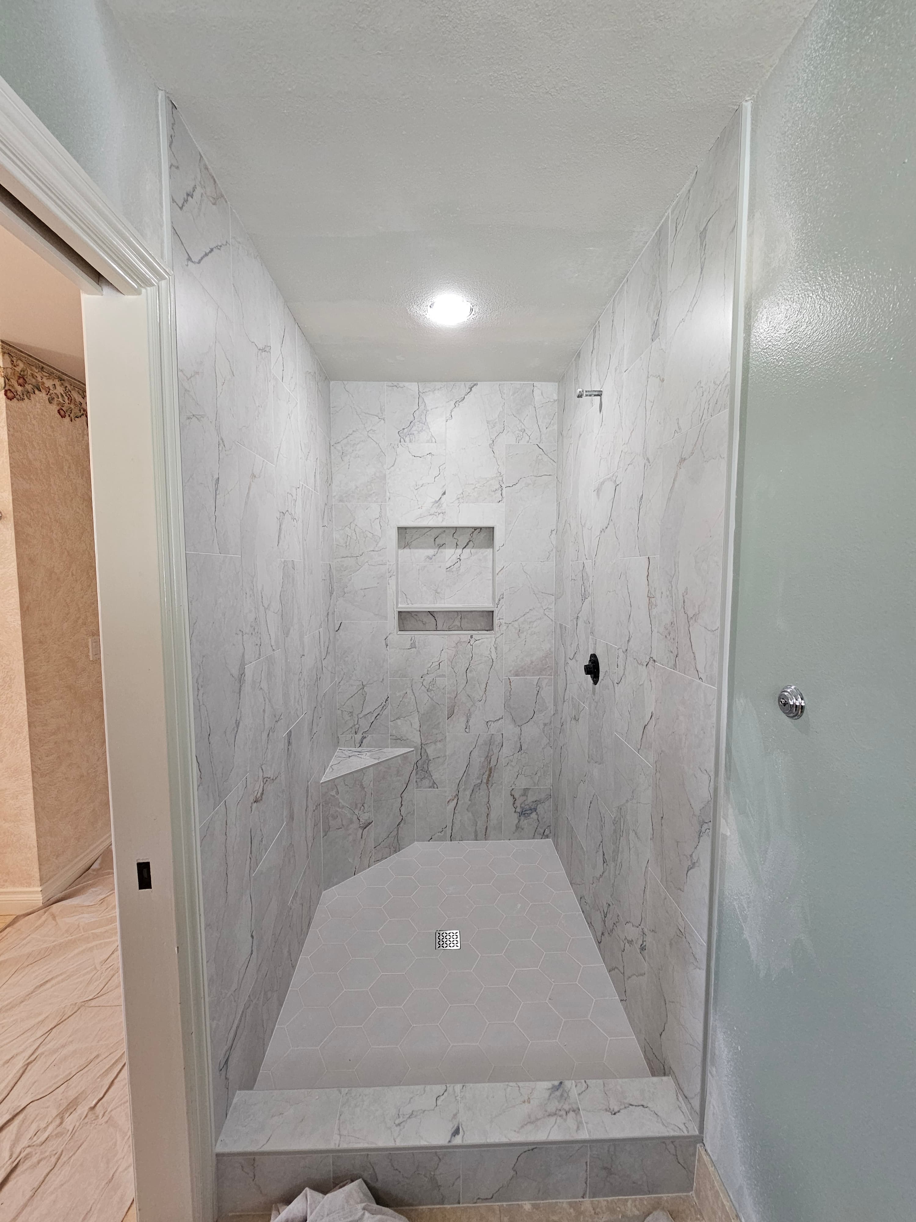 Spa-inspired Fallbrook walk-in shower with marble hexagon wall tiles and large-format flooring