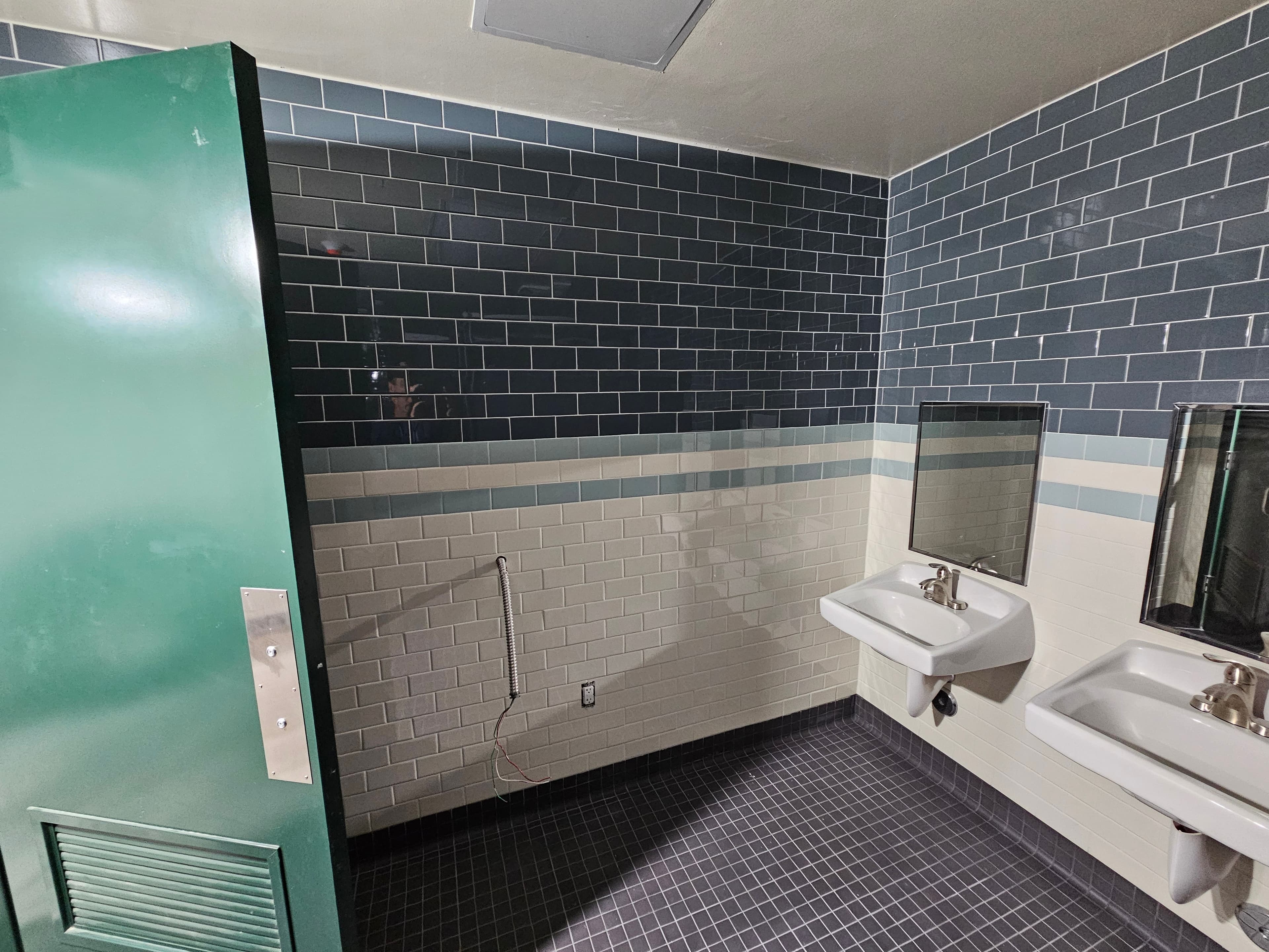 Irvine commercial restroom with deep blue and white subway tile, decorative center stripe, and wall-mount sinks