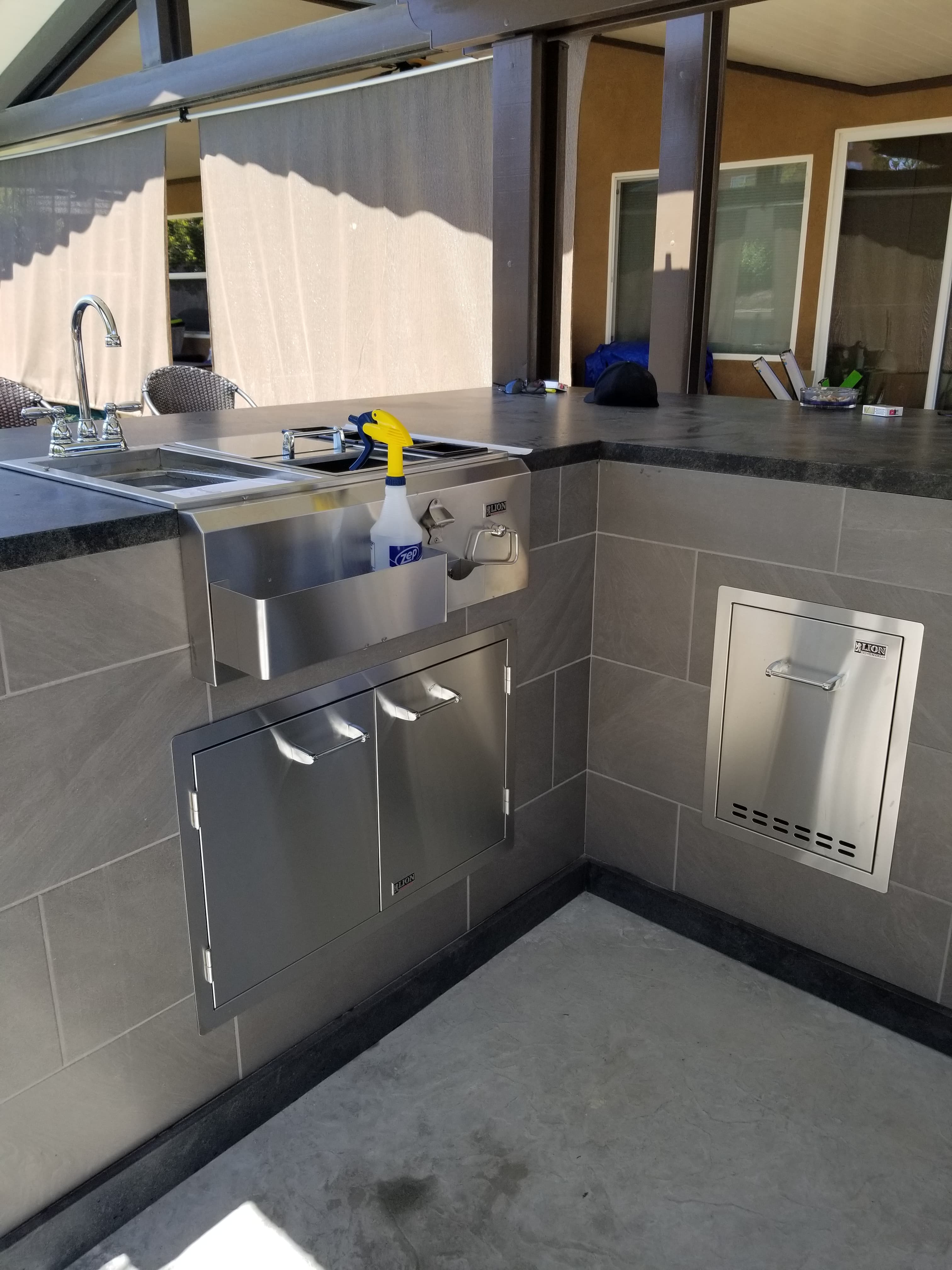 Menifee outdoor BBQ corner with stainless storage cabinet and prep sink set into a dark gray porcelain-clad surround