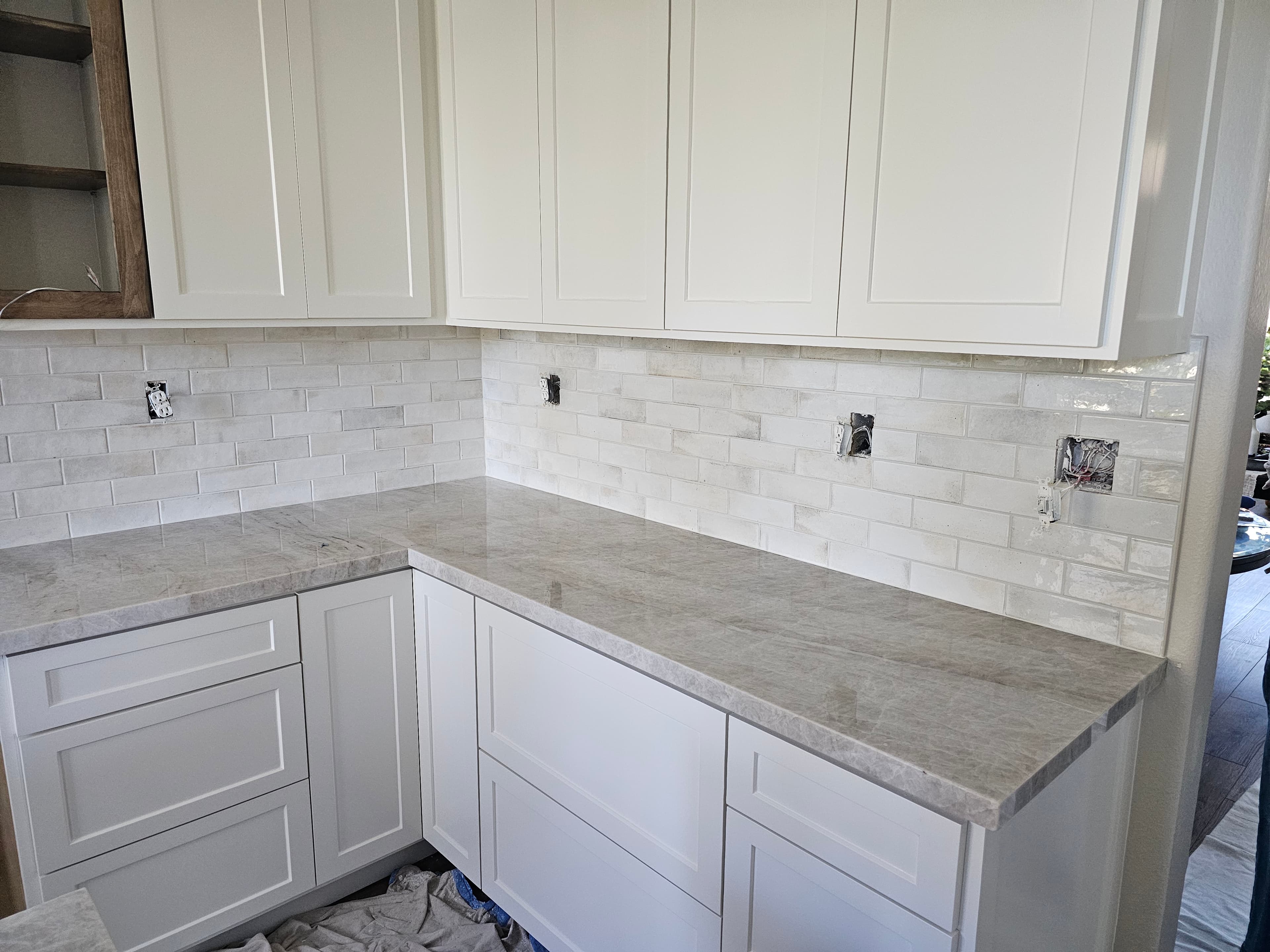 Mission Viejo kitchen with crisp white subway tile backsplash above marble countertop and shaker cabinetry