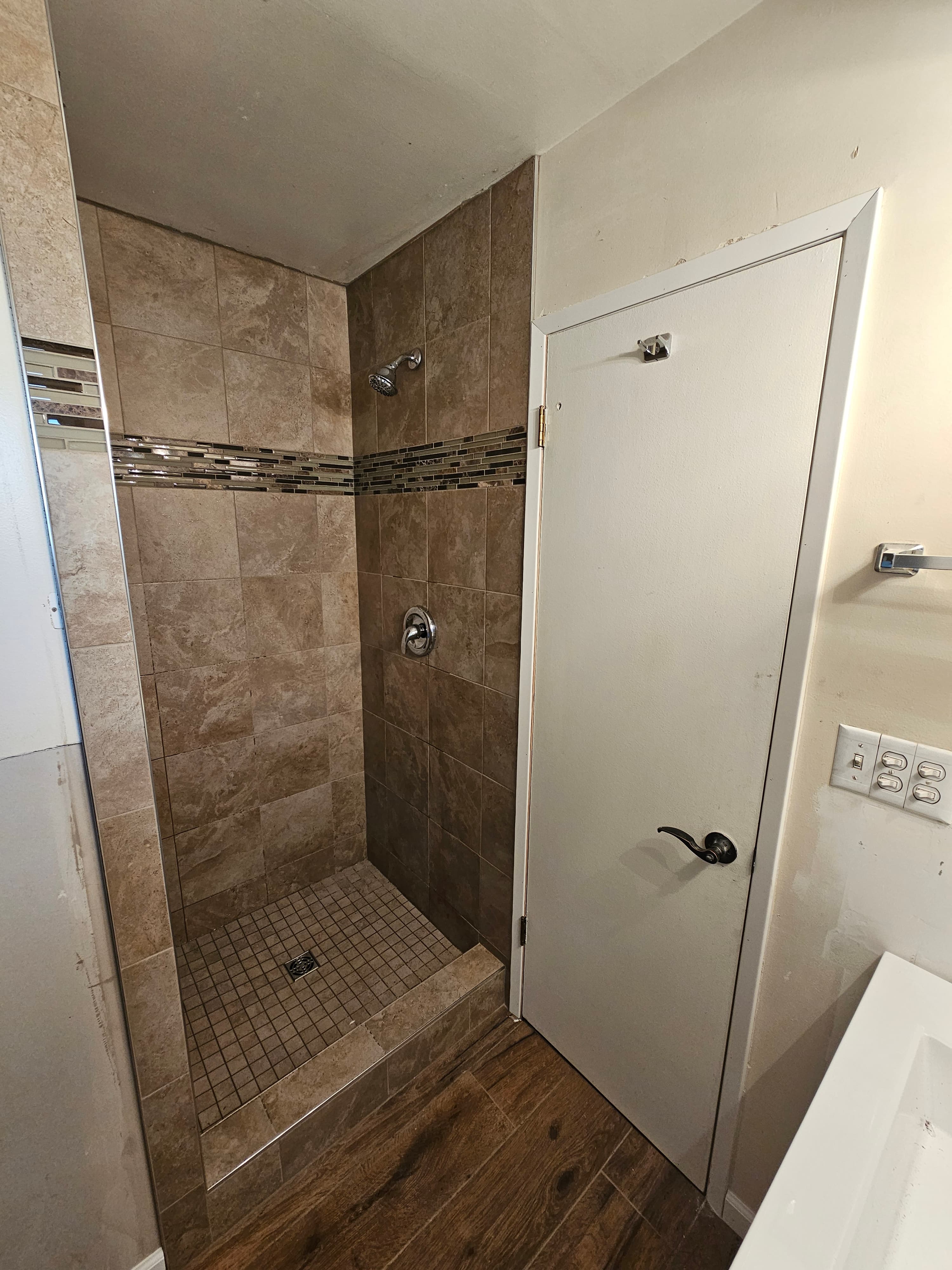 Newly renovated Orange, CA shower with warm travertine tile and modern linear drain