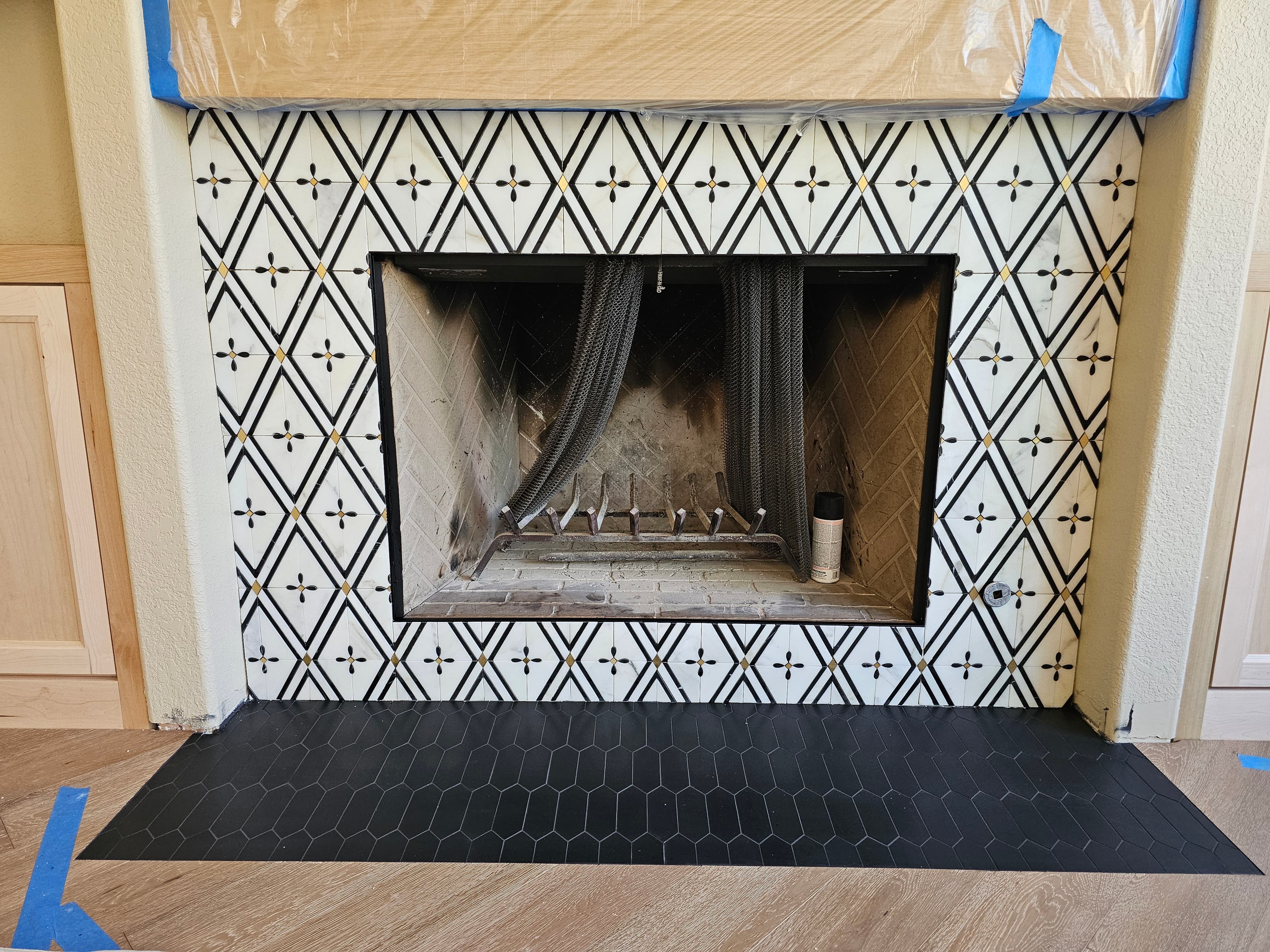 Custom Rancho Santa Margarita fireplace surround in black and white diamond-pattern tile with black hexagon mosaic hearth