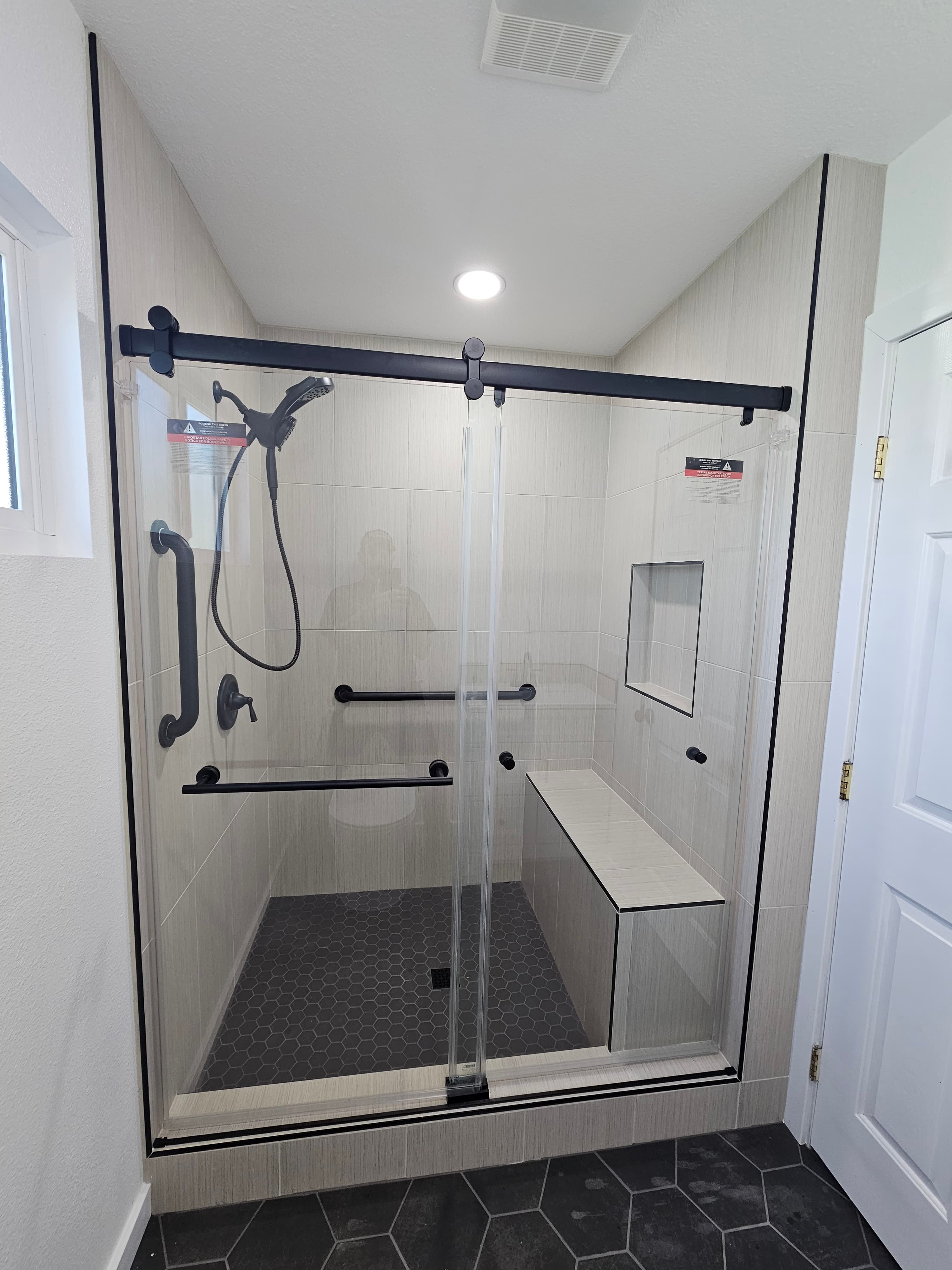 Modern frameless walk-in shower with linear tile and charcoal hexagon feature wall, Riverside, CA